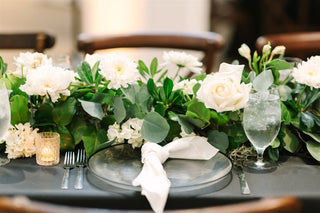 A closeup shot of white flowers and greeneries as a table centerpiece for a wedding.