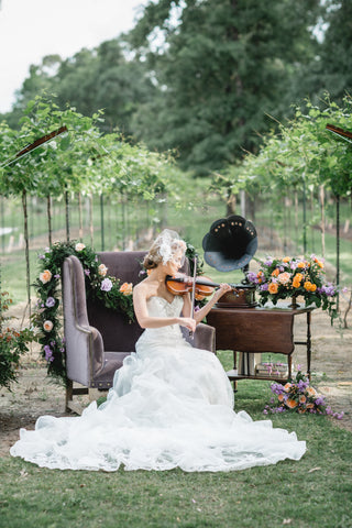 A bride playing a violin with beautiful floral designs by montgomery texas florist.